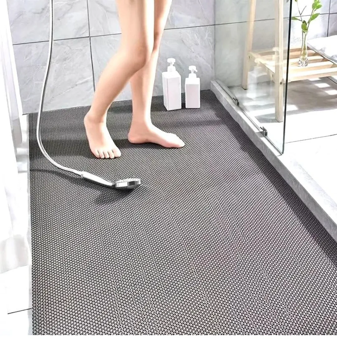 Grey perforated anti-slip mat covering a wet shower floor